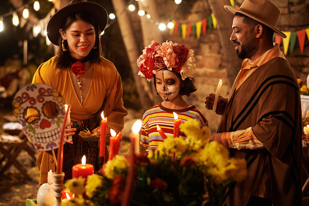 Family celebrating Day of the Dead in Puerto Vallarta with traditional face paint, candles, and marigolds around a colorful altar